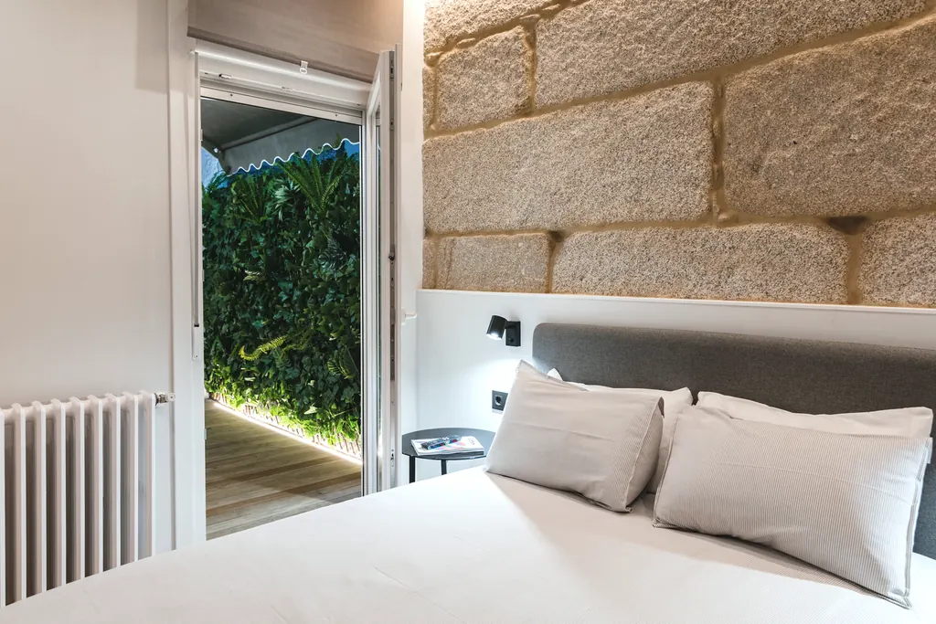 Vivienda E58: dormitorio con muro de granito y jardín vertical