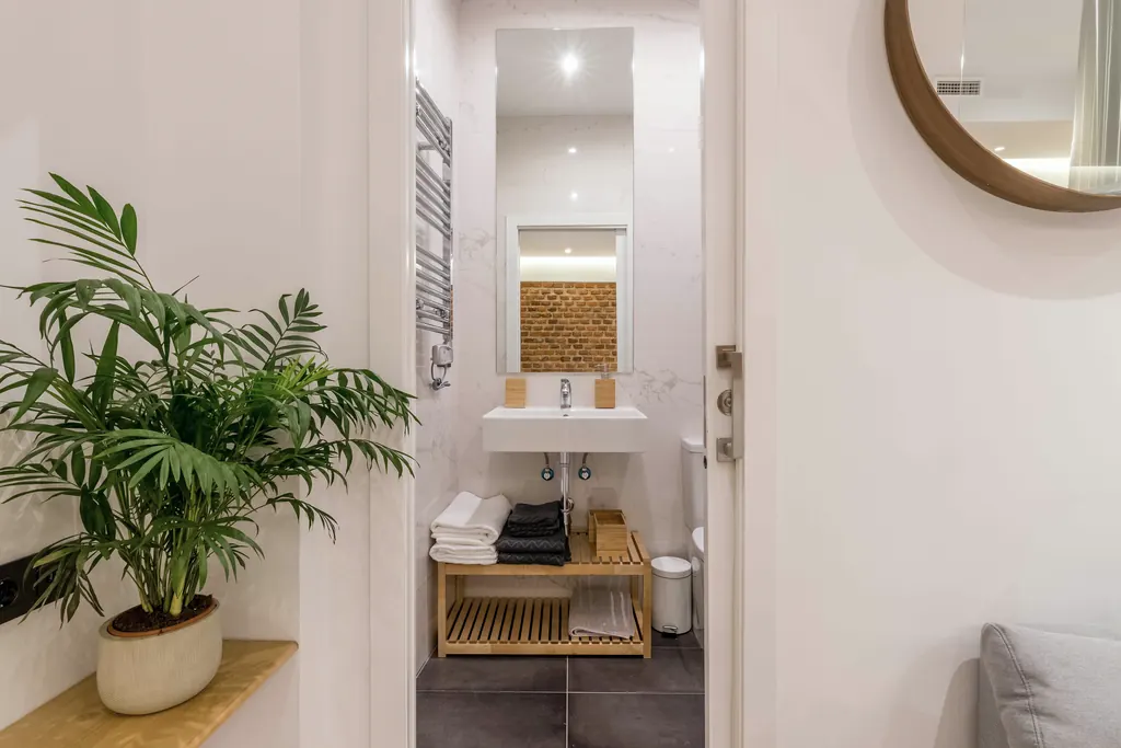 Vivienda LS7: baño con lavabo de madera y espejo redondo